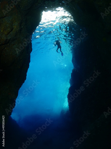 snorkelling girl underwater exploring a cave cavern eneterance under water deep water scenery 