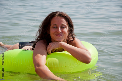 happy woman suntan in sea water on inflatable ring