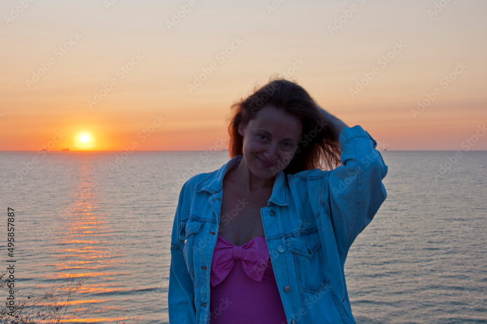 positive young woman look at summer sunset sun and sky with seascape positive young woman look at summer sunset sun and sky with seascape
