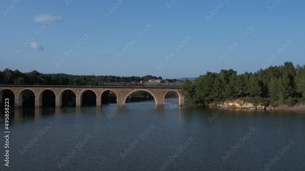 Aerial drone view flying over a reservoir and under a railway bridge in the afternoon light. El Reagajo. Castellon, Spain. Aerial drone view flying over a reservoir and under a railway bridge in the afternoon light. El Reagajo. Castellon, Spain.