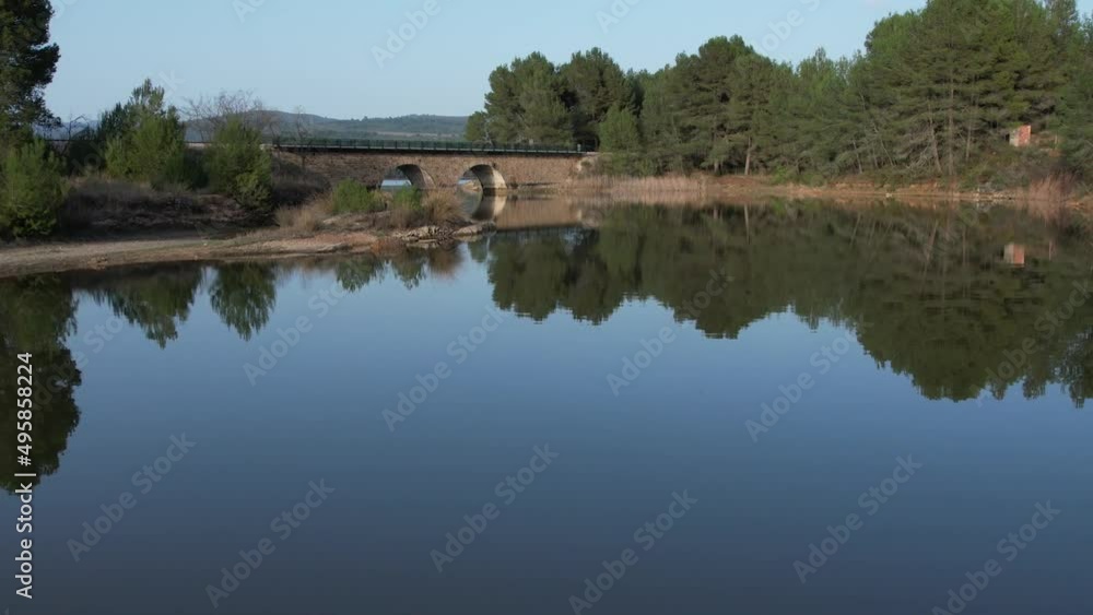 Aerial drone view flying over a reservoir and a railway bridge with still water like a mirror, daylight. El Regajo. Castellon, Spain. Aerial drone view flying over a reservoir and a railway bridge with still water like a mirror, daylight. El Regajo. Castellon, Spain.