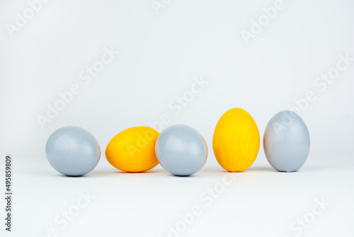 Five easter colored yellow and gray decorated eggs on white background. Happy Easter card with copy space for text. Minimal easter style.