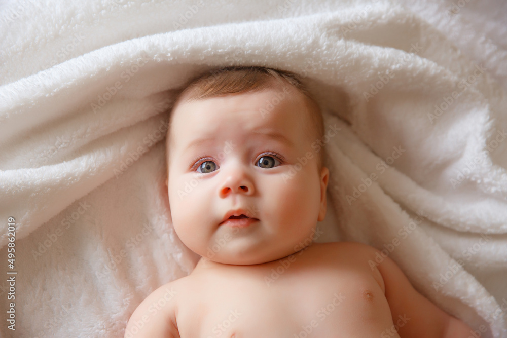 baby is wearing diapers and a white towel in bedroom. top view . A newborn baby is resting in bed after a bath or shower. Children's room. Textiles and bedding for children baby is wearing diapers and a white towel in bedroom. top view . A newborn baby is resting in bed after a bath or shower. Children's room. Textiles and bedding for children