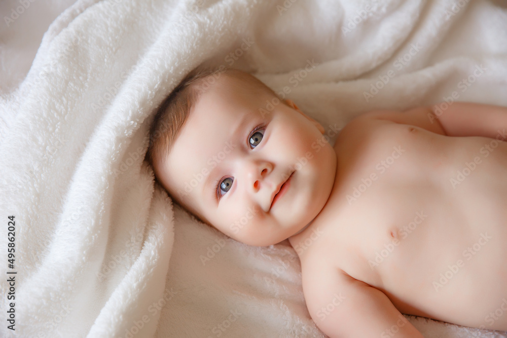 baby is wearing diapers and a white towel in bedroom. top view . A newborn baby is resting in bed after a bath or shower. Children's room. Textiles and bedding for children baby is wearing diapers and a white towel in bedroom. top view . A newborn baby is resting in bed after a bath or shower. Children's room. Textiles and bedding for children