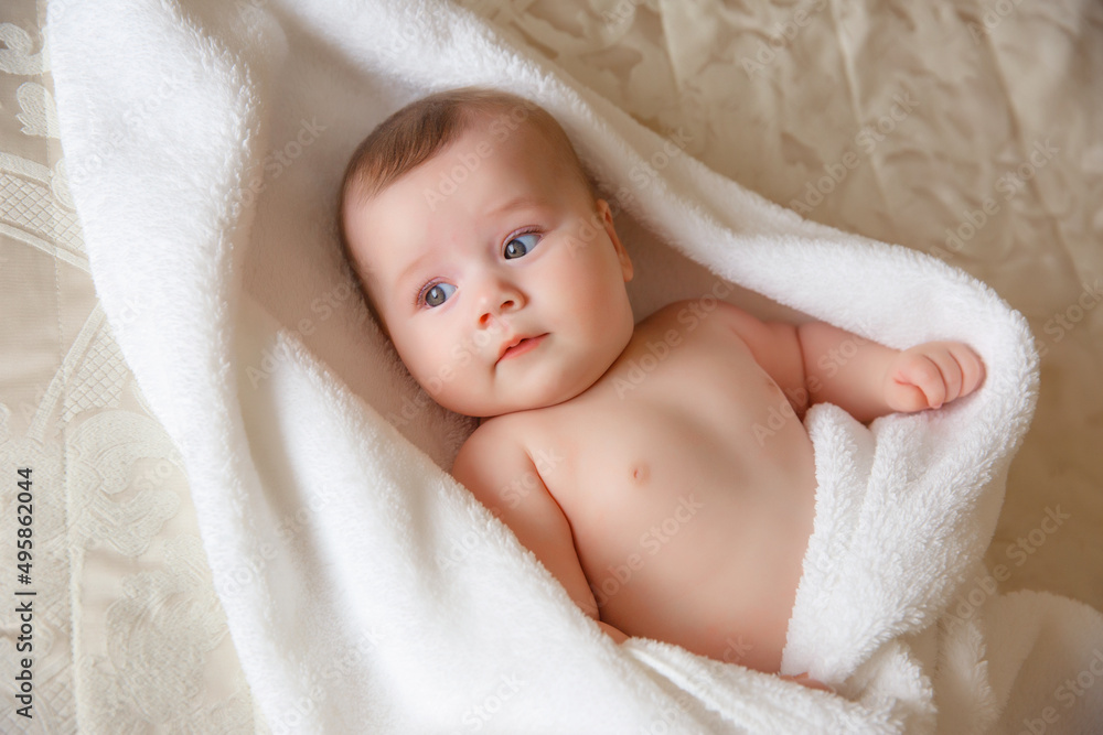 baby is wearing diapers and a white towel in bedroom. top view . A newborn baby is resting in bed after a bath or shower. Children's room. Textiles and bedding for children baby is wearing diapers and a white towel in bedroom. top view . A newborn baby is resting in bed after a bath or shower. Children's room. Textiles and bedding for children