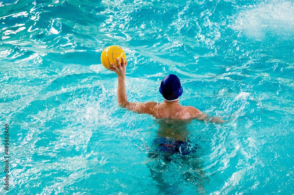 Young men play water polo in a swimming pool 