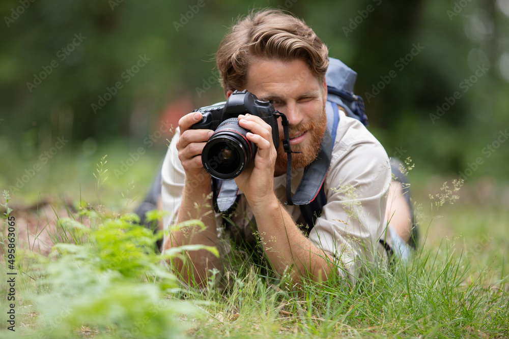 young man is lying on a grass while he photographs young man is lying on a grass while he photographs