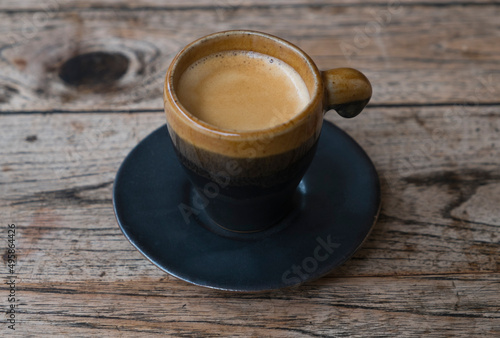 Coffee in espresso cup and saucer on wooden table