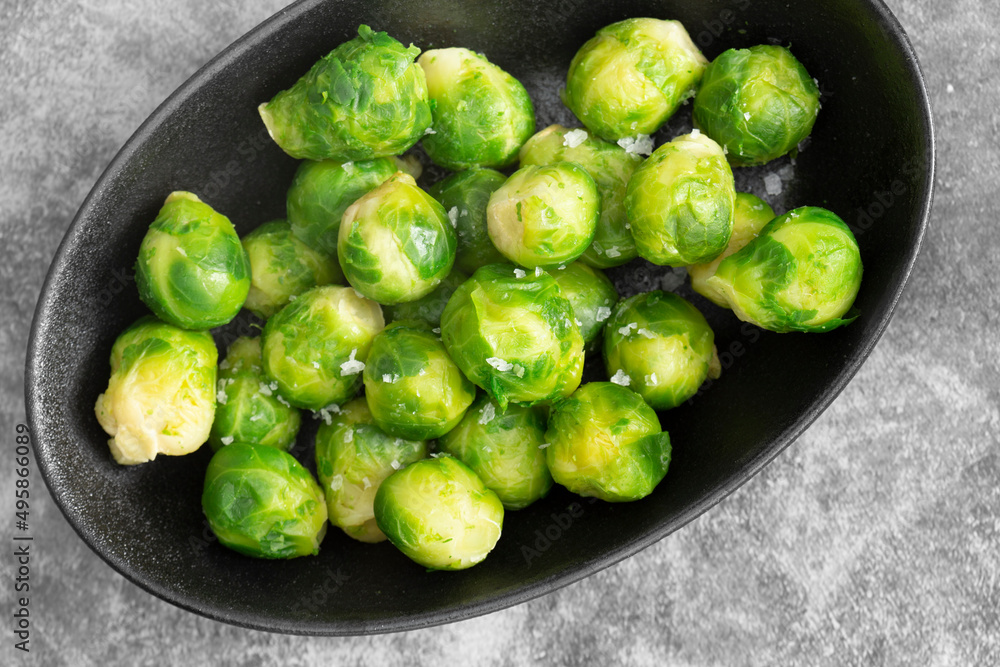 Brussels sprouts seasoned with sea salt in a black dish. On a stone background Brussels sprouts seasoned with sea salt in a black dish. On a stone background