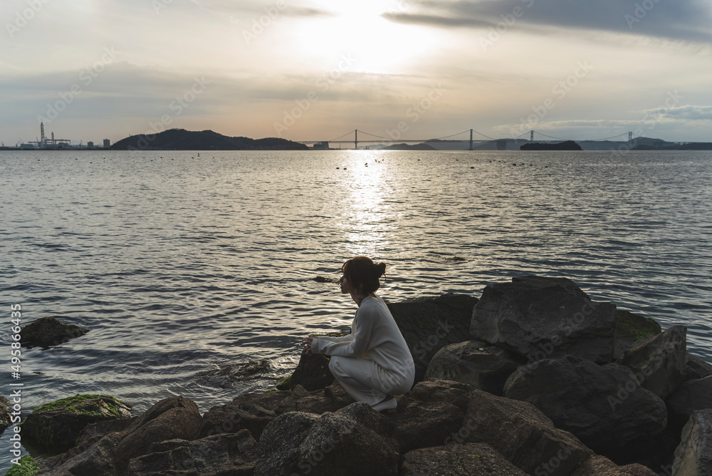 夕暮れの海岸線を歩く女性 夕暮れの海岸線を歩く女性