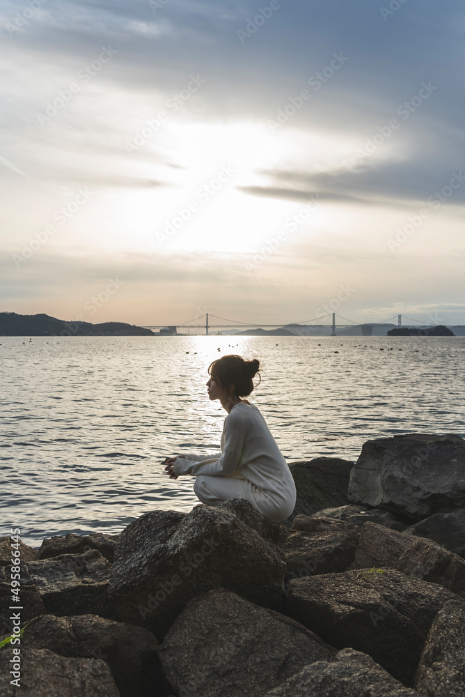 夕暮れの海岸線を歩く女性