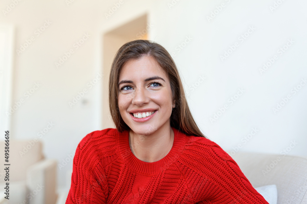Happy young woman sitting on sofa at home and looking at camera. Portrait of comfortable woman in winter clothes relaxing on armchair. Portrait of beautiful woman smiling and relaxing during autumn. Happy young woman sitting on sofa at home and looking at camera. Portrait of comfortable woman in winter clothes relaxing on armchair. Portrait of beautiful woman smiling and relaxing during autumn.