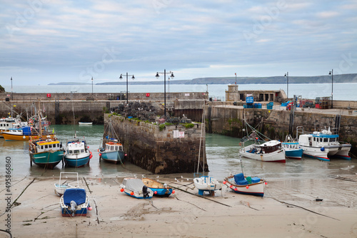 Low tide at a Cornish harbour, sea coast fishing village, boats moored, beached on the sand.  photo