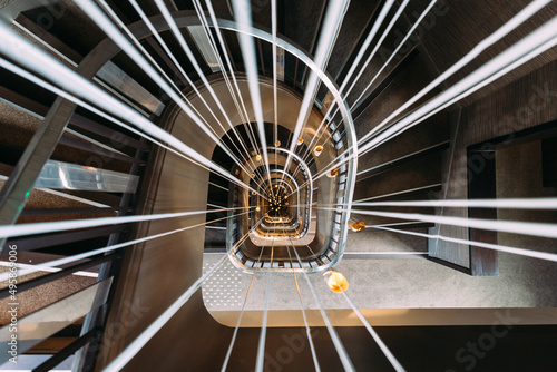 Modern spiral staircase with lights in the middle. Optical perspective. Stairway in hotel in Paris.