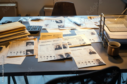 Workplace of fbi agent with criminal profiles, evidences and clues, stacks of packed documents or journals with information photo