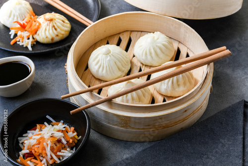 Xiao long bao or baozi dumplings in   bamboo steamers,  chopsticks and bowl of sauce. Chinese food delivery photo