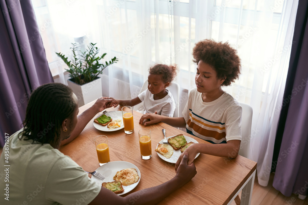 Black family praying before breakfast at home