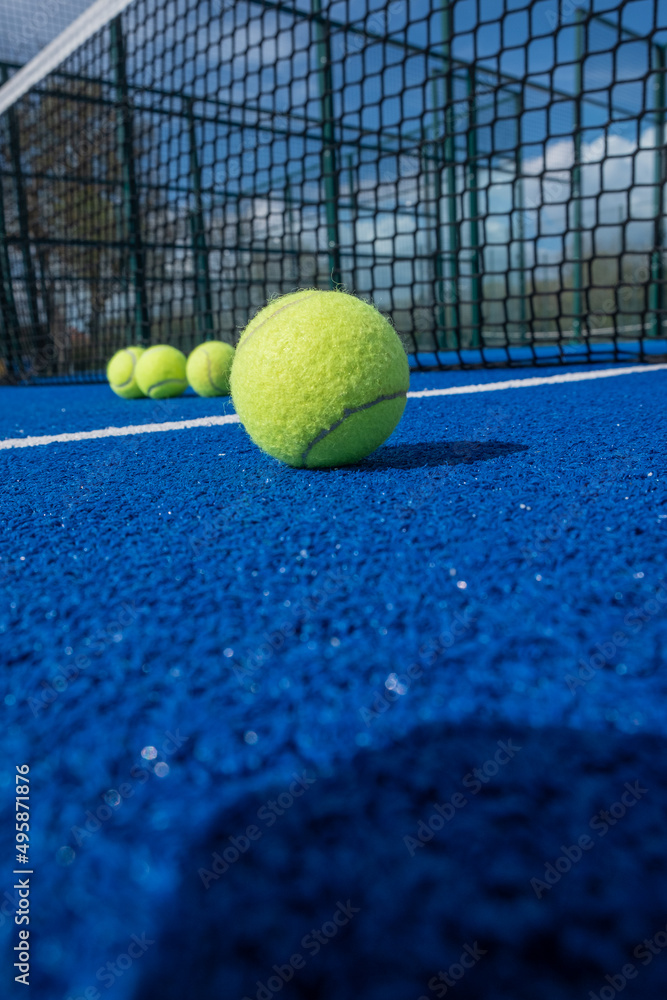 selective approach, paddle tennis balls in front of the net of a blue paddle tennis court