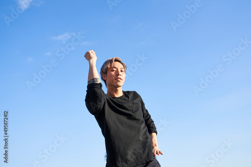 Man dancing outdoors with sky and bent elbow