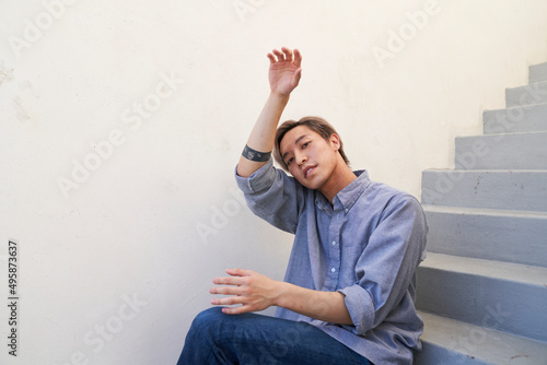 Man sitting on stairs with arm over head