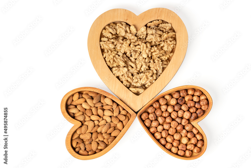 Variety of nuts in wooden cups in the shape of a heart isolated on a white background. Variety of nuts in wooden cups in the shape of a heart isolated on a white background.