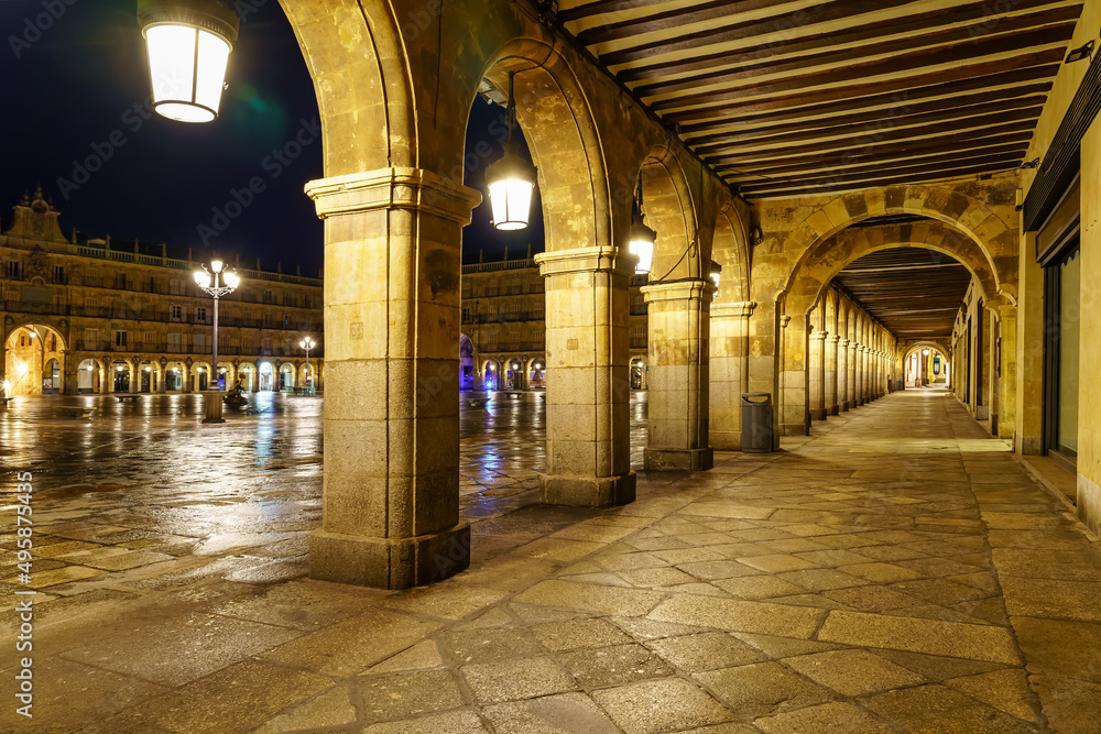 Night and illuminated view of the main square of Salamanca and its medieval stone arches.
