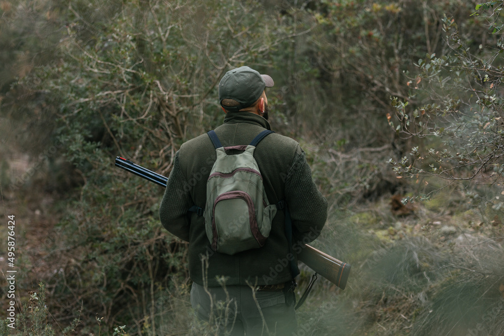 Man with rifle seeking animals while hunting in woods