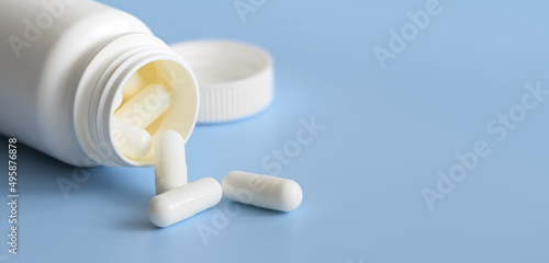 White Pills scattered from white plastic medicine container