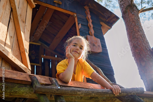 Photos Happy pretty girl looking down from the beautiful creative handmade treehouse in