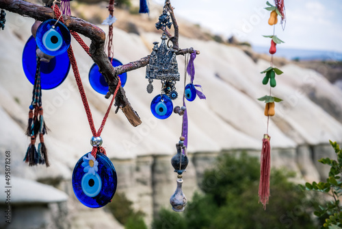 Amulets against evil eye hanging on tree in front of sandy mountain in Cappadocia, Turkey