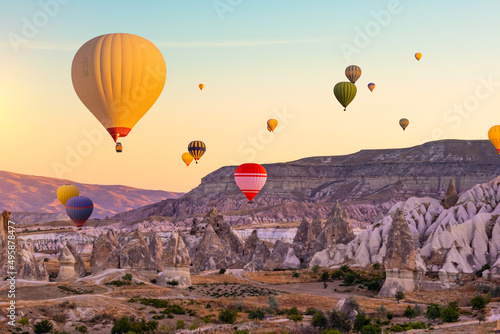 Hot air balloons in sunset sky floating over mountains