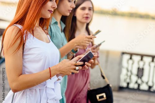 Happy best friends walking in city with modern smartphones