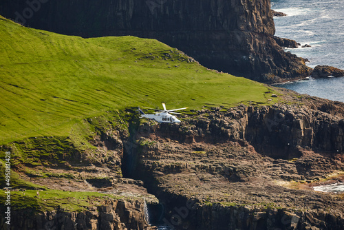 Helicopter flying over mykines island in Faroe archipelago. Denmark photo
