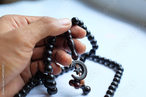 A man reading a prayer with beads, Islamic religious icons in hands close-up on yellow background photo