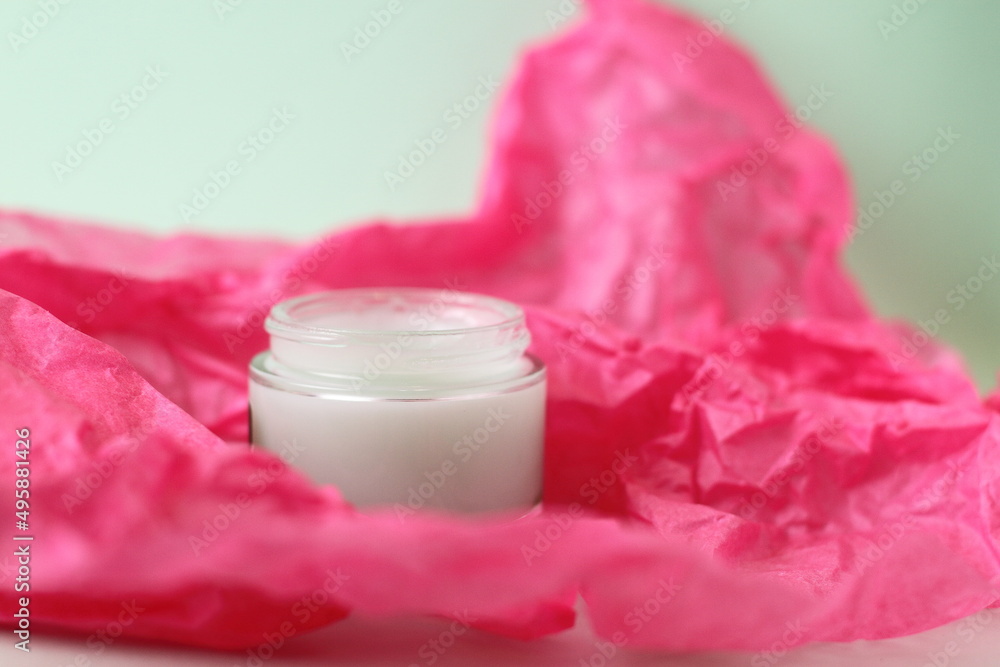 Green cream in crystal jar on pink paper background Green cream in crystal jar on pink paper background