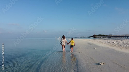 Mother and son walking on a solitary beach