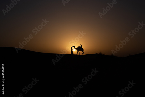 silhouette of a person and camel on a sunset