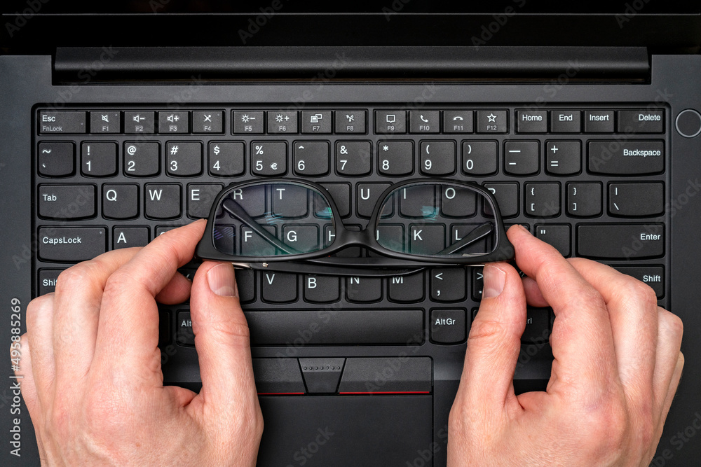 Hands holding glasses on laptop keyboard Hands holding glasses on laptop keyboard