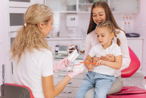 Little girl with mom visiting female dentist at dental clinic
