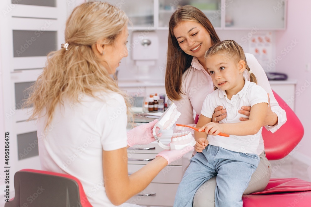 Little girl with mom visiting female dentist at dental clinic Little girl with mom visiting female dentist at dental clinic