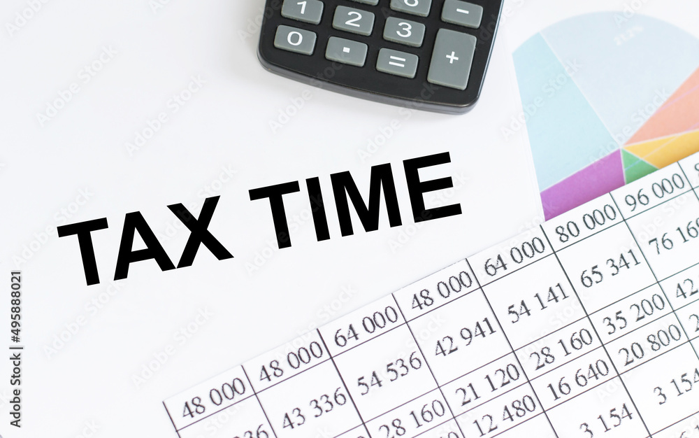 tax time inscription on the notebook next to the calculator, accounting items and financial charts tax time inscription on the notebook next to the calculator, accounting items and financial charts