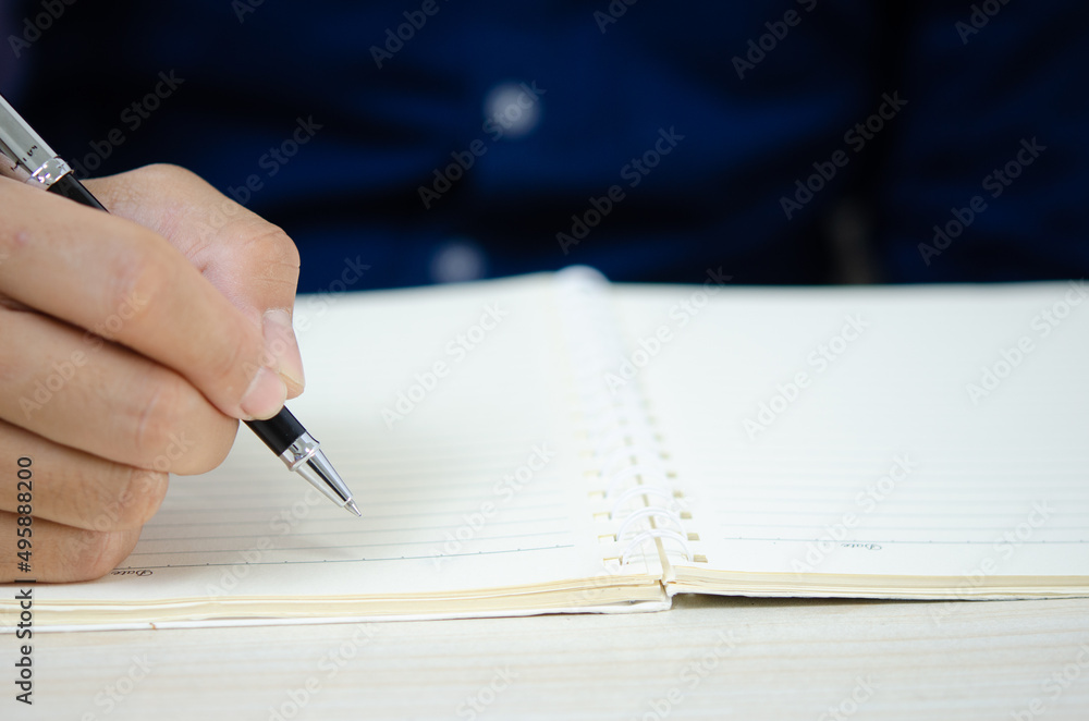 close up holding a pen and writing at the notebook. close up holding a pen and writing at the notebook.