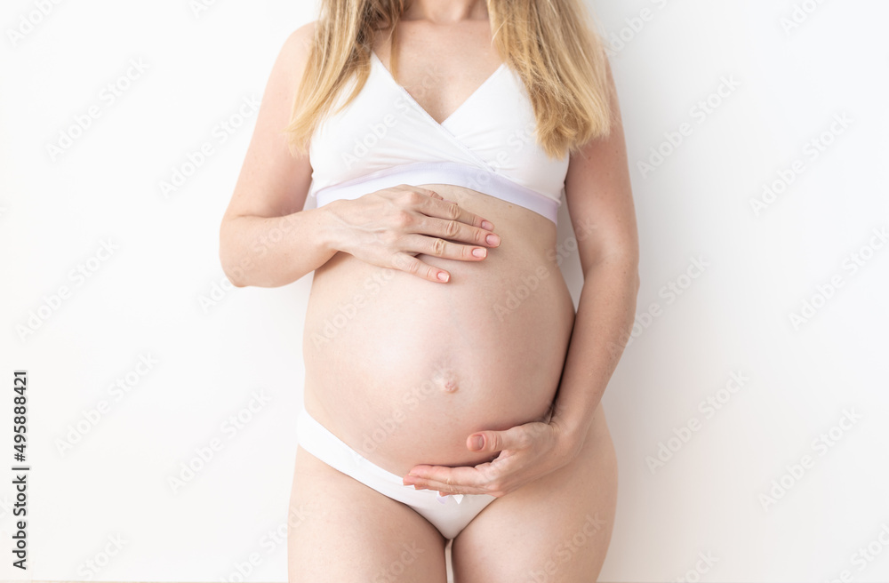 pregnant woman standing holding her hands on her stomach pregnant woman standing holding her hands on her stomach