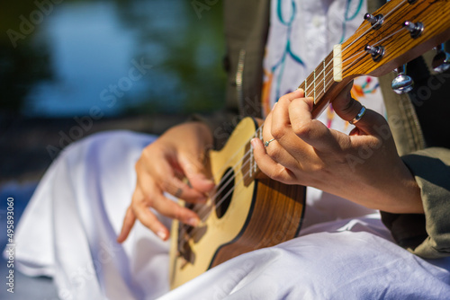 Woman learning to play ukulele outdoors. Enjoyment of music