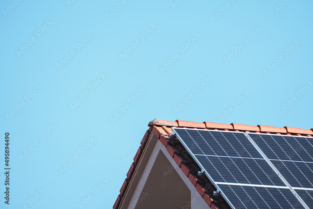 Fototapeta premium Solar photovoltaic panels on a house roof for renewable energy with blue sky