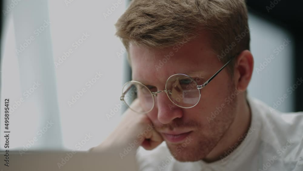 smart caucasian man with glasses is reading info on laptop screen, closeup view of face smart caucasian man with glasses is reading info on laptop screen, closeup view of face