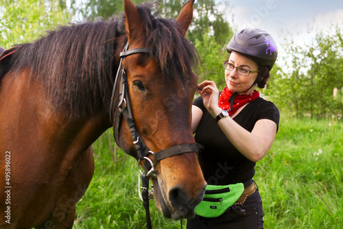 A woman harnesses her horse before riding.