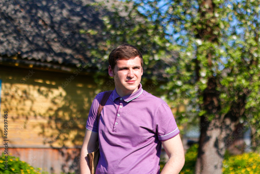 Defocus handsome man outdoors portrait. Man smiling, looking in the camera. Young men in purple shirt on nature summer background. Out of focus Defocus handsome man outdoors portrait. Man smiling, looking in the camera. Young men in purple shirt on nature summer background. Out of focus