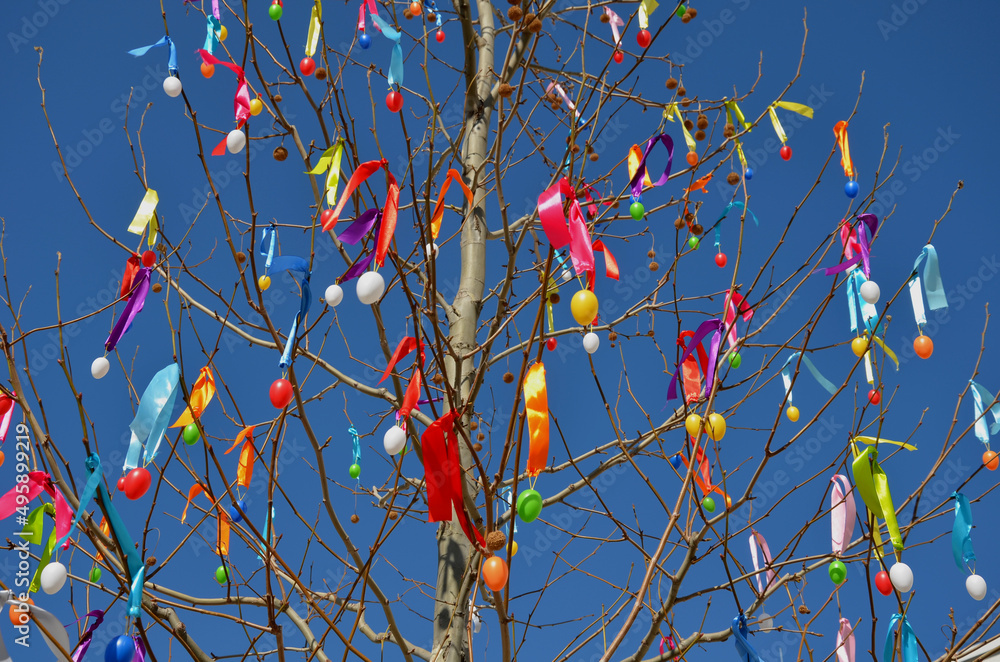 easter tree with plastic egg decorations and colorful ribbons hanging in large quantities on sycamore branches. The blue sky together creates beautiful kitsch