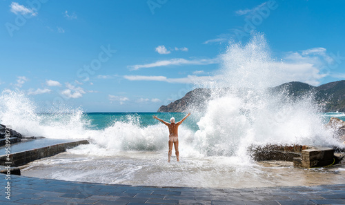 naked man by the sea in the summer is hitting by gigantic waves